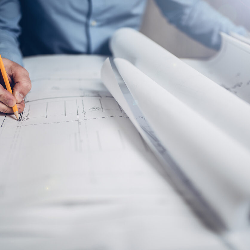 Hands of an architect or engineer drawing on blueprints